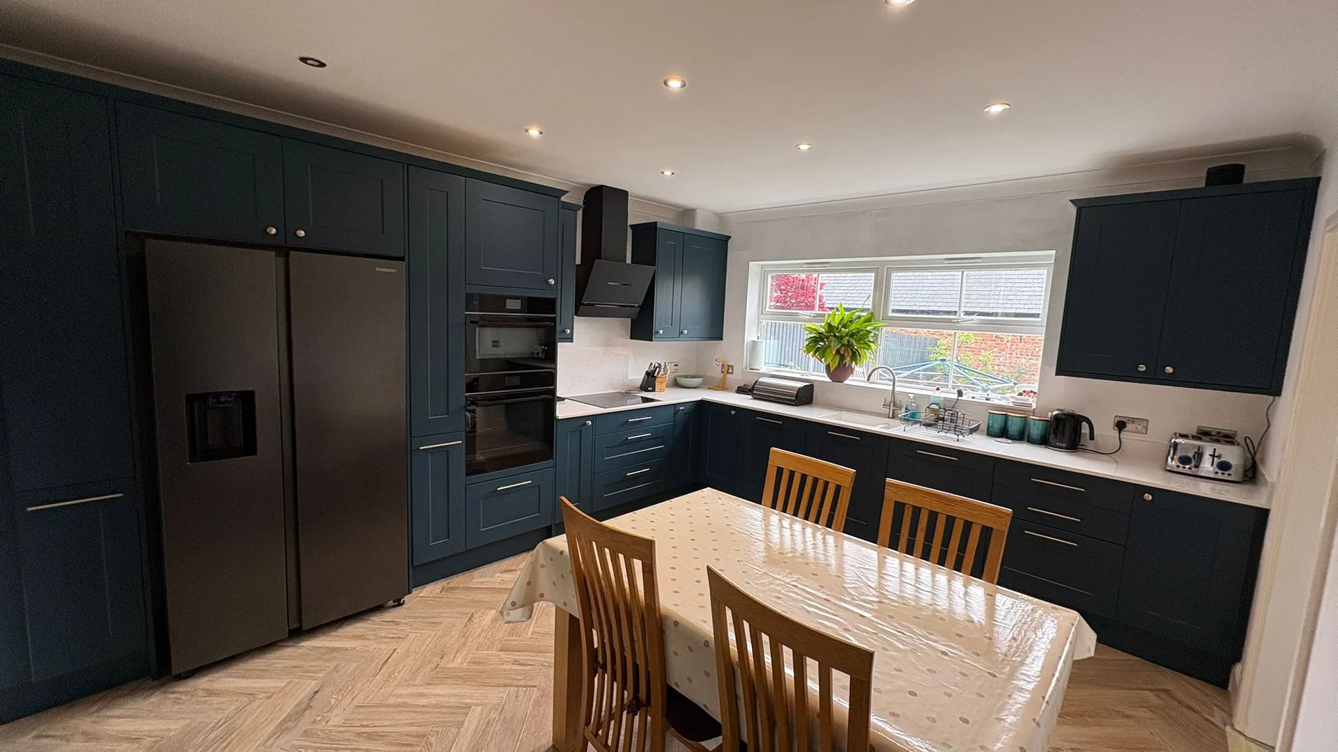 Open plan kitchen and dining room finished in navy shaker units with quartz worktops