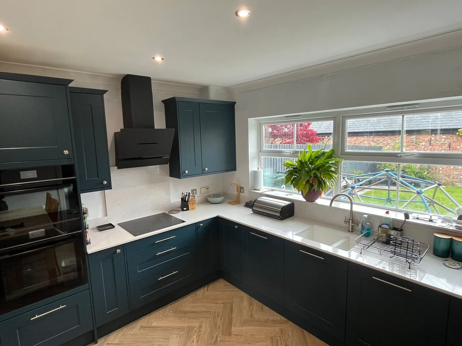 Finished navy shaker kitchen with extractor hood, built in ovens and quartz worktops
